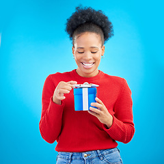 Image showing Smile, birthday and a black woman with a gift on a blue background for happiness or a surprise. Holding, box and a young African girl with a present for a celebration isolated on a studio backdrop