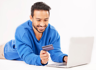 Image showing Studio laptop, credit card and happy man online shopping for tech discount, promotion or e commerce sales. Customer payment, trading store and relax financial banking person on white background floor