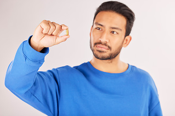 Image showing Healthcare, showing and a man with a pill on a studio background for a virus, covid or supplement. Sick, medical and an Asian person with a tablet, medication or vitamin c medicine for wellness