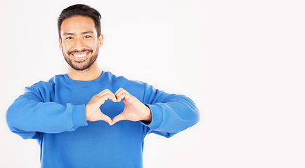 Image showing Portrait, heart and hands of man in studio, white background and care for kindness on mockup space. Happy asian male model with finger shape for love icon, thank you and emoji in support of freedom