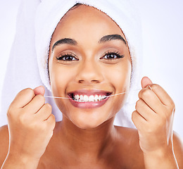 Image showing Dental floss, teeth and face of a woman for health and wellness in studio. Portrait of a young female model flossing, cleaning and self care for fresh breath, hygiene and shine on a white background