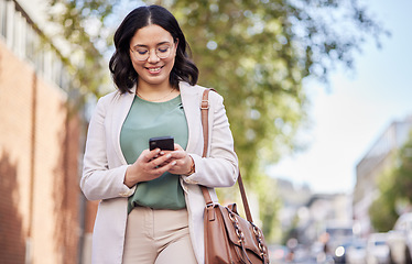 Image showing Phone, city and happy business woman for outdoor communication, networking and social media. Chat, typing and mobile search of young professional person walking and travel in urban street for contact