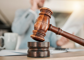 Image showing Closeup, gavel and law on table, office and attorney man in blurred background with phone call for networking. Advocate, lawyer or judge with legal hammer, paperwork or documents for court evidence