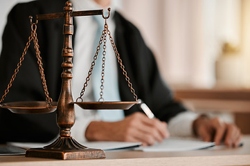 Image showing Closeup, scales and law on table, office and attorney man in blurred background with reading for crime analysis. Advocate, lawyer or judge with legal hammer, paperwork or documents for court evidence