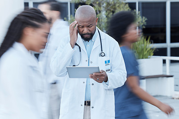 Image showing Tablet, black man and doctor with stress in busy hospital, fatigue or burnout. Tech, medical professional or person with problem, crisis or challenge, headache or anxiety in mistake, fail or disaster