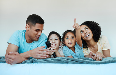 Image showing Father, mom and kids on bed, watching tv and smile for comedy, funny movie or pointing in family home. Happy parents, children and watch television show with streaming, subscription or laugh together