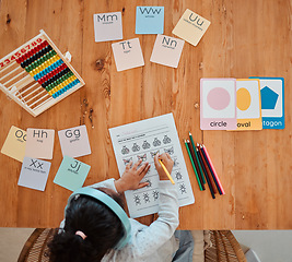 Image showing Above, child and girl writing on table for homework or remote learning in home for development, growth and education. Kid, working and studying for school, math and writing on paper in living room