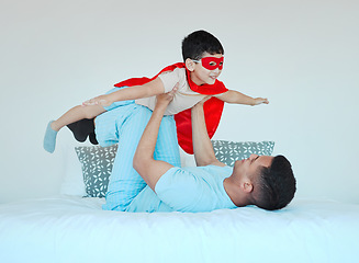 Image showing Airplane, bedroom and dad playing with his kid for bonding, fun or happiness at their home. Happy, smile and young father relaxing with his boy child in a superhero costume on the bed at family house