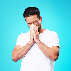 Image showing Tissue, nose and man in studio for sick allergy, cold and influenza on blue background. Asian male model sneeze wit hayfever, allergies and infection of virus bacteria, health care and congestion