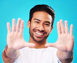 Image showing Portrait, hands and man frame face in studio to review profile picture on blue background. Happy young asian model planning perspective of photography, selfie and creative inspiration for border sign