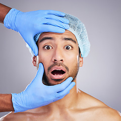 Image showing Man, hands and face for plastic surgery in studio with fear, pain and scared for cosmetics by background. Doctor gloves, dermatology surgeon and patient with wow, surprise and facial transformation