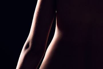 Image showing Beauty, body and person on black background for creative lighting, shadow and silhouette. Aesthetic, skincare and closeup of waist in dark studio with macro of skin for art deco, wellness and glow