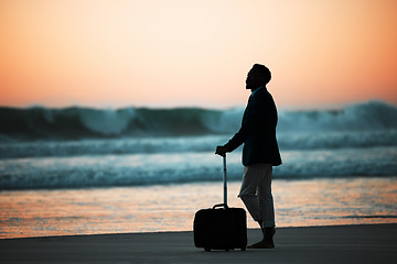 Image showing Sunset, beach and man with suitcase for travel, vacation and break in nature with freedom and solo trip. Ocean, Silhouette, male at the sea at sunrise for holiday, experience and abroad relocation