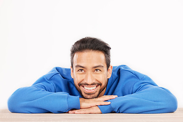 Image showing Thinking, wonder and face of man on a white background with ideas, brainstorming and dream by table. Happy, mockup space and isolated male person resting on desk for choice or decision in studio