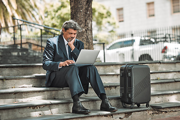 Image showing Travel, email and businessman with laptop in the city for communication and booking a flight online. Serious, working and mature corporate manager with a computer and luggage for a ticket on the web