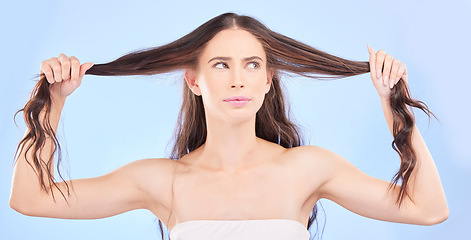 Image showing Thinking, woman and damaged hair in studio with cosmetics, haircare or confused face for beauty, problem or split ends. Frustrated, girl and ideas for hairstyle in salon or growth on blue background