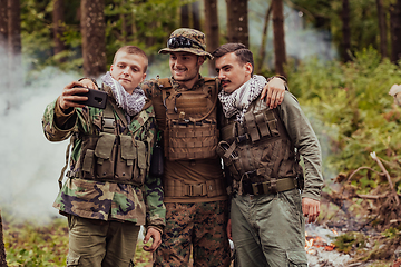 Image showing Team of soldiers and terrorist taking selfie with smartphone in the forest