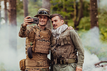 Image showing Team of soldiers and terrorist taking selfie with smartphone in the forest