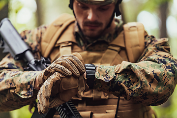 Image showing American marine corps special operations soldier preparing tactical and commpunication gear for action battle closeup