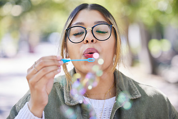 Image showing Face of woman blowing bubbles in park, garden and freedom for fun, good mood and carefree personality. Happy, young and female gen z girl with soap bubble wand outdoor to relax on summer holiday