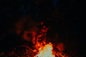 Image showing Soldier in Action at Night in the Forest Area. Night Time Military Mission jumping over fire