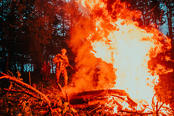 Image showing Soldier in Action at Night in the Forest Area. Night Time Military Mission jumping over fire