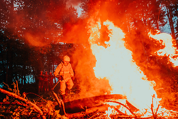 Image showing firefighter hero in action danger jumping over fire flame to rescue and save