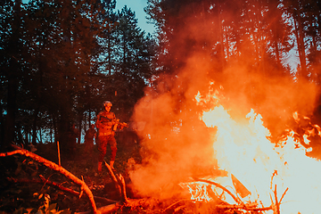 Image showing Soldier in Action at Night in the Forest Area. Night Time Military Mission jumping over fire