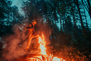 Image showing firefighter hero in action danger jumping over fire flame to rescue and save