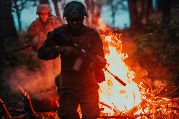 Image showing Soldier in Action at Night in the Forest Area. Night Time Military Mission jumping over fire