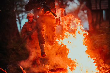 Image showing Soldier in Action at Night in the Forest Area. Night Time Military Mission jumping over fire