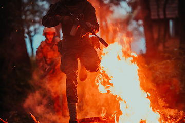 Image showing Soldier in Action at Night in the Forest Area. Night Time Military Mission jumping over fire