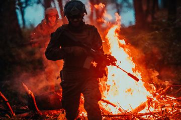 Image showing Soldier in Action at Night in the Forest Area. Night Time Military Mission jumping over fire