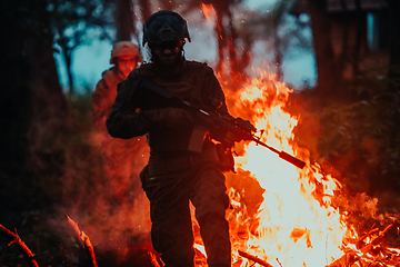 Image showing Soldier in Action at Night in the Forest Area. Night Time Military Mission jumping over fire