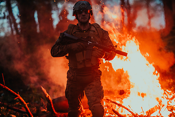 Image showing Soldier in Action at Night in the Forest Area. Night Time Military Mission jumping over fire