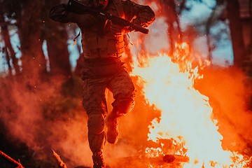 Image showing Soldier in Action at Night in the Forest Area. Night Time Military Mission jumping over fire