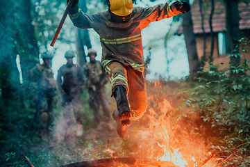 Image showing firefighter hero in action danger jumping over fire flame to rescue and save