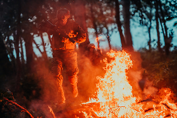 Image showing Soldier in Action at Night in the Forest Area. Night Time Military Mission jumping over fire