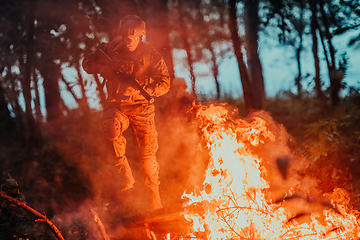 Image showing Soldier in Action at Night in the Forest Area. Night Time Military Mission jumping over fire