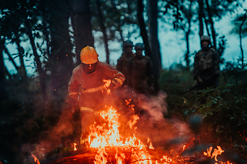 Image showing firefighter hero in action danger jumping over fire flame to rescue and save