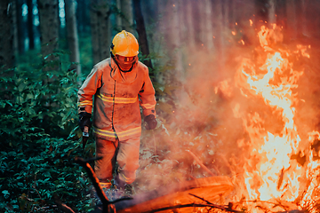 Image showing firefighter hero in action danger jumping over fire flame to rescue and save