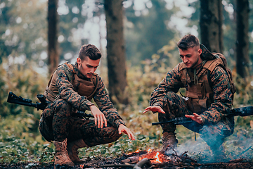 Image showing Two exhausted soldiers sitting by the fire after a weary and heavy war battle