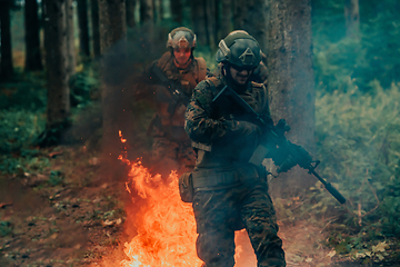 Image showing Soldier in Action at Night in the Forest Area. Night Time Military Mission jumping over fire