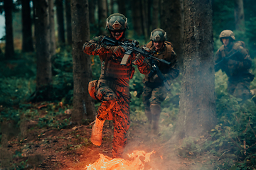 Image showing Soldier in Action at Night in the Forest Area. Night Time Military Mission jumping over fire