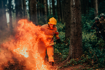 Image showing firefighter hero in action danger jumping over fire flame to rescue and save