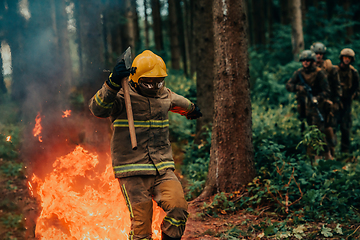 Image showing firefighter hero in action danger jumping over fire flame to rescue and save