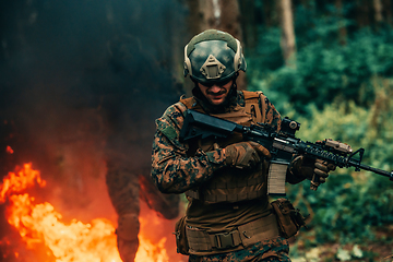 Image showing Soldier in Action at Night in the Forest Area. Night Time Military Mission jumping over fire