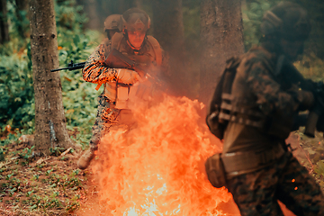 Image showing Soldier in Action at Night in the Forest Area. Night Time Military Mission jumping over fire