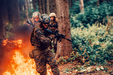 Image showing Soldier in Action at Night in the Forest Area. Night Time Military Mission jumping over fire