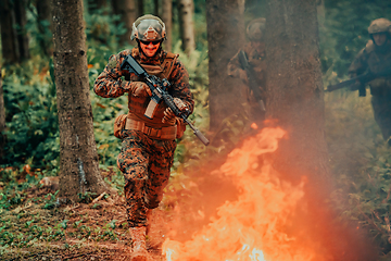 Image showing Soldier in Action at Night in the Forest Area. Night Time Military Mission jumping over fire